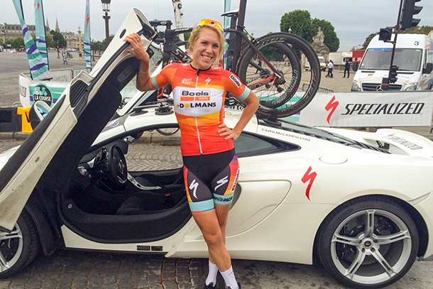 Ellen van Dijk posing happily on front of a McLaren sportscar | Racefietsblog.nl